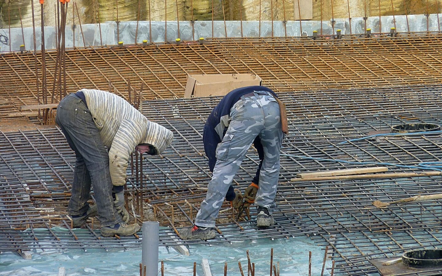 Workers tying steel reinforcement bars over a concrete slab